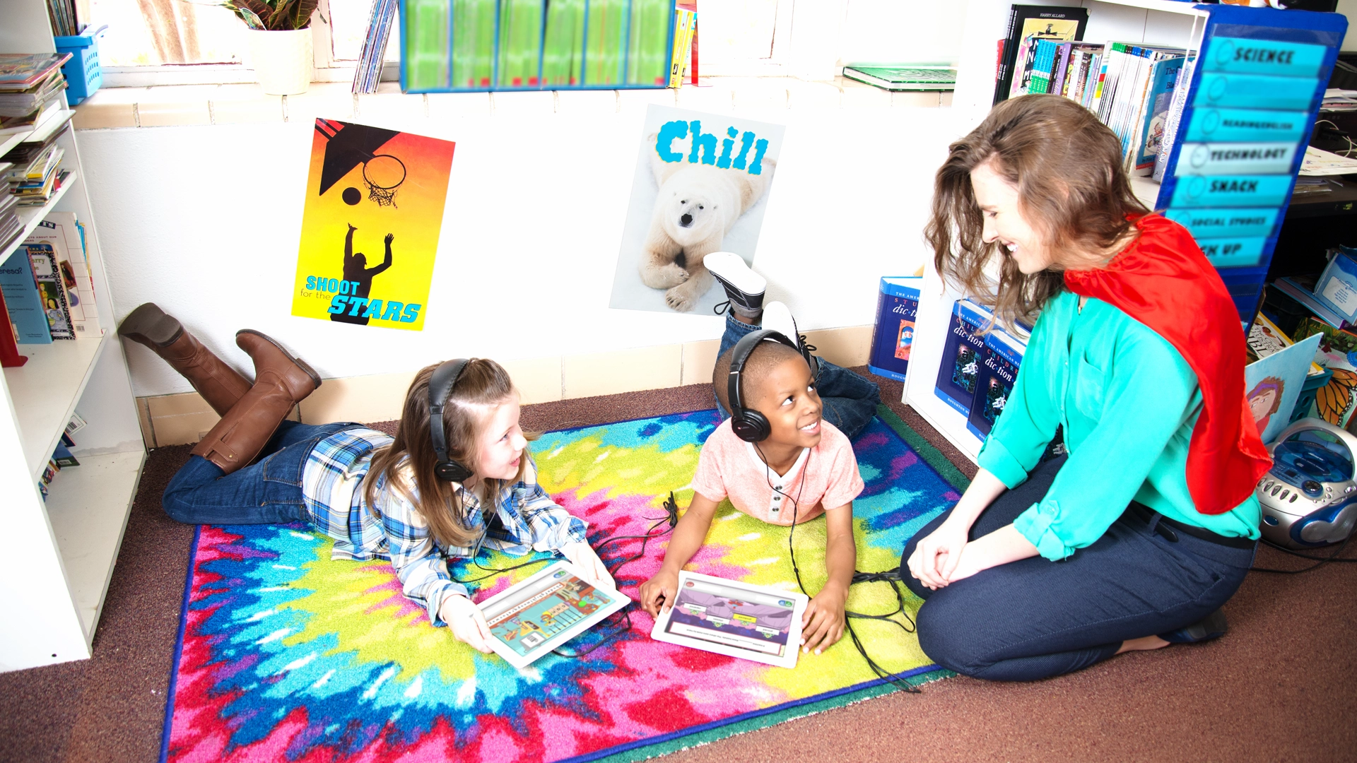 An educator helping two students using Istation Reading on an iPad.